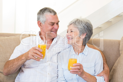 Senior couple sitting on couch drinking orange juice