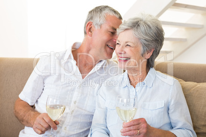 Senior couple sitting on couch drinking white wine