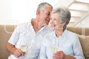 Senior couple sitting on couch drinking white wine