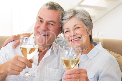 Senior couple sitting on couch having white wine