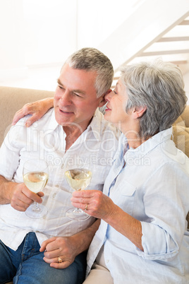 Senior couple sitting on couch having white wine