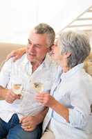 Senior couple sitting on couch having white wine