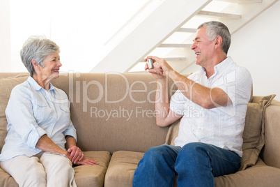 Retired man taking photo of his partner on the couch