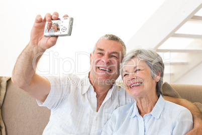 Senior couple sitting on couch taking a selfie