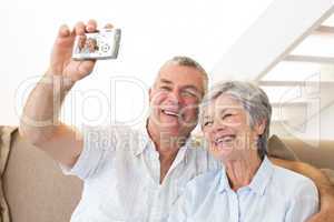 Senior couple sitting on couch taking a selfie