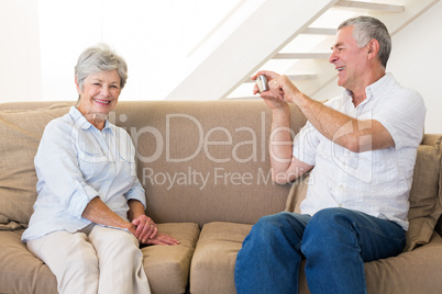 Retired man taking photo of his partner on the couch