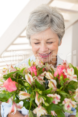 Retired woman holding bouquet of flowers and smiling