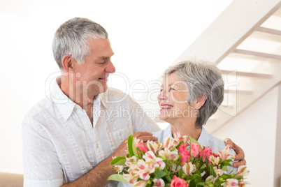 Senior couple smiling at each other holding bouquet of flowers
