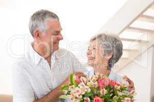 Senior couple smiling at each other holding bouquet of flowers