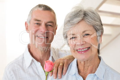 Senior man offering a rose to his partner smiling at camera
