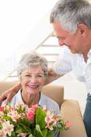 Senior man giving his partner a bouquet of flowers smiling at ca