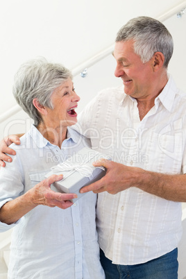 Senior man giving his surprised partner a gift