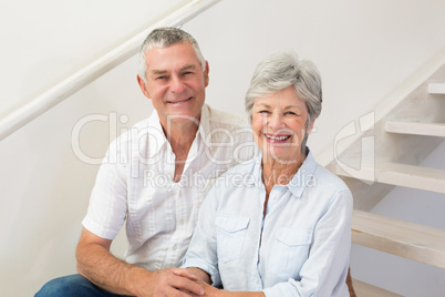 Senior couple sitting on stairs smiling at camera