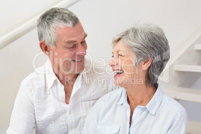 Senior couple sitting on stairs smiling at each other