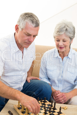 Senior couple sitting on sofa playing chess