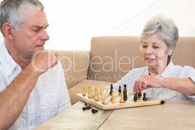 Senior couple sitting on floor playing chess