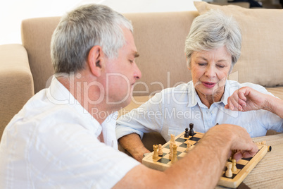 Senior couple sitting on floor playing chess