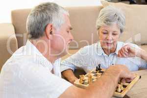 Senior couple sitting on floor playing chess