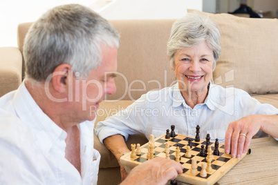 Senior couple sitting on floor playing chess