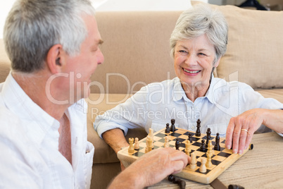 Senior couple sitting on floor playing chess