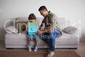 Father and son with gift box sitting in living room