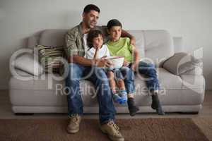 Father and sons with popcorn bowl watching tv in the living room