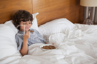 Young boy eating breakfast in bed