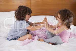 Siblings clapping hands in bed
