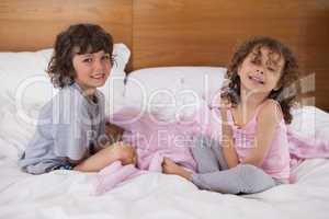Portrait of happy siblings sitting in bed