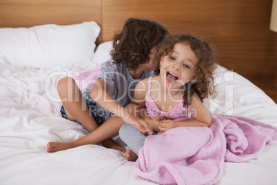 Happy siblings sitting in bed