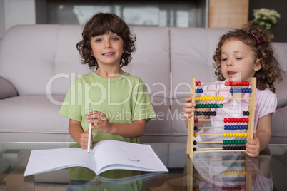 Siblings with book and abacus in living room
