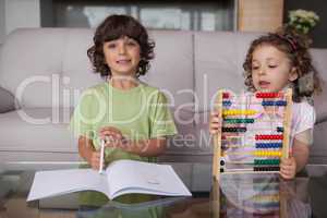 Siblings with book and abacus in living room