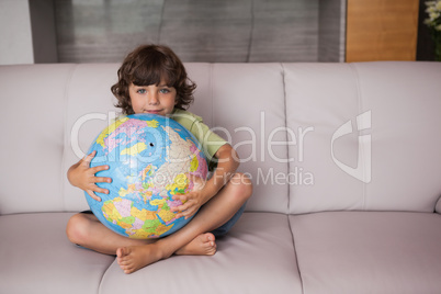 Portrait of a happy kid with globe in the living room