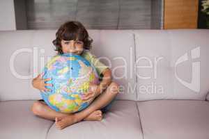 Portrait of a happy kid with globe in the living room
