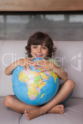 Portrait of a happy kid with globe in living room