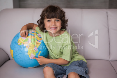 Portrait of a happy kid with globe in living room