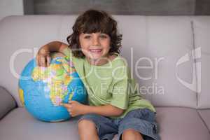 Portrait of a happy kid with globe in living room