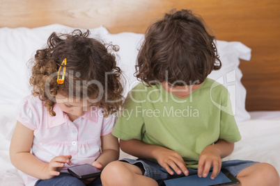 Kids using digital tablet and cellphone in bed
