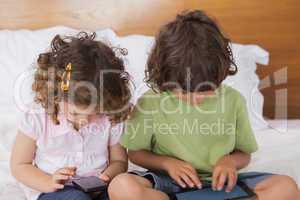 Kids using digital tablet and cellphone in bed