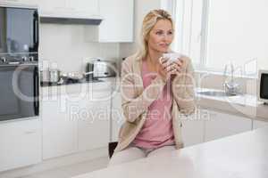 Thoughtful woman drinking coffee in kitchen