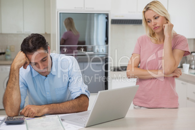 Unhappy couple with bills and laptop in kitchen