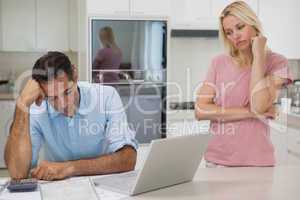 Unhappy couple with bills and laptop in kitchen