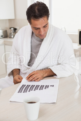 Casual businessman looking at graphs in kitchen