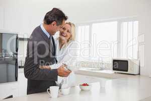 Woman embracing businessman in the kitchen