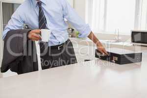 Well dressed man with coffee cup picking briefcase in kitchen
