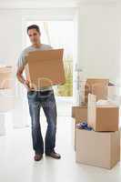 Smiling man carrying boxes in new house