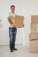 Smiling man carrying boxes in new house