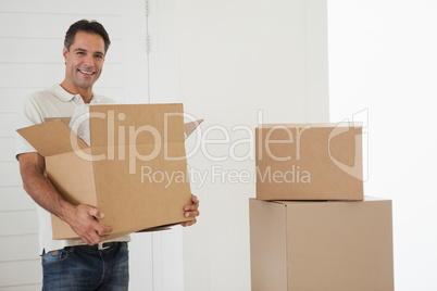 Smiling man carrying boxes in new house