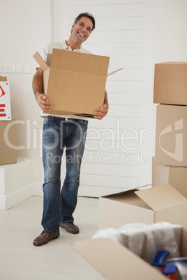 Smiling man carrying boxes in new house