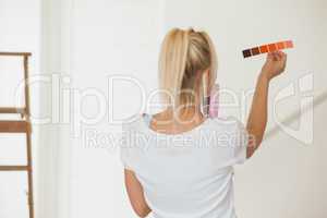 Rear view of woman choosing color for painting a room